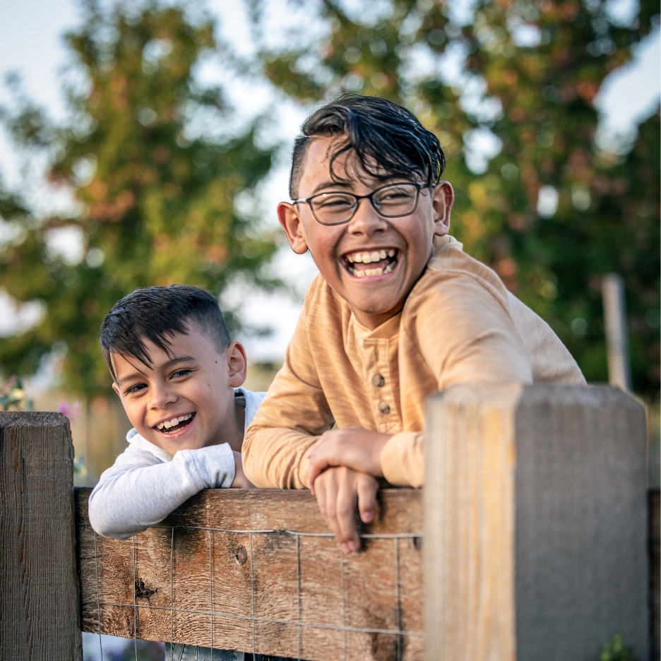 Two children leaning against a fence.