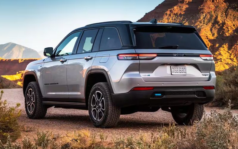 A silver SUV from Centerra is parked outdoors on a dirt road, surrounded by the breathtaking desert landscape and mountains of Loveland, CO, all under a clear blue sky.